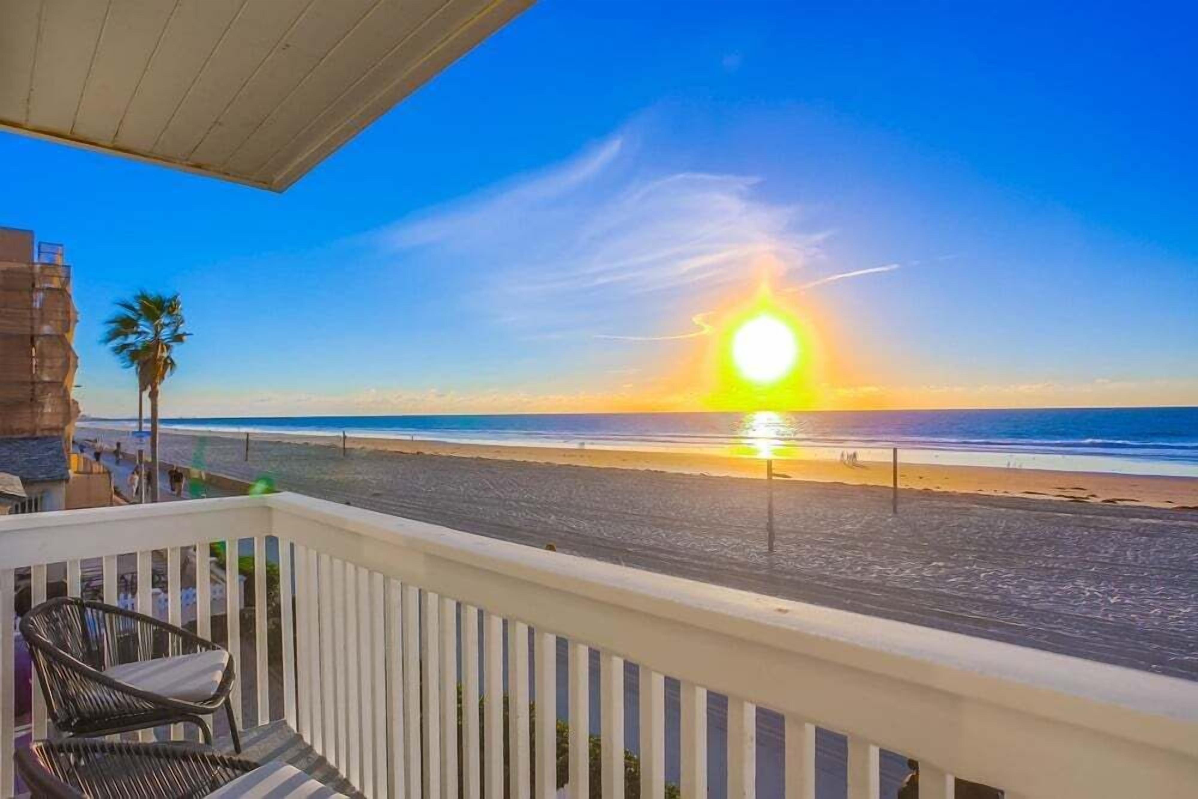 Un balcón con vistas a la playa y al océano al atardecer.