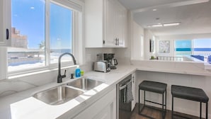 A modern kitchen with white cabinetry, a stainless steel sink, and a coffee maker.