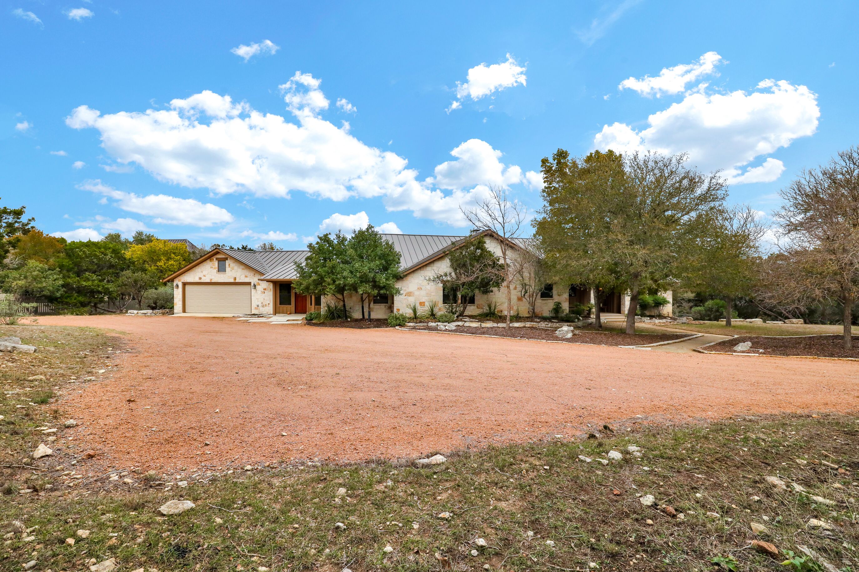 A two-story house with a garage, surrounded by a gravel driveway and landscaped garden.