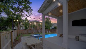 Patio con piscina, terraza de madera y zona de estar al aire libre.
