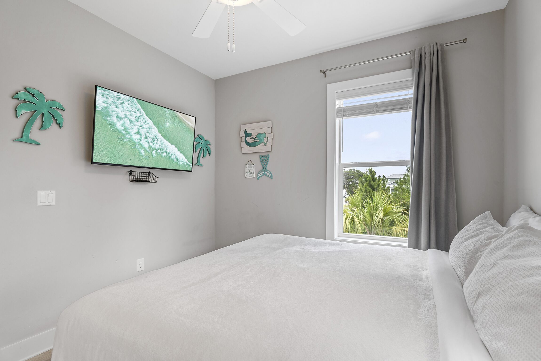 A bedroom with a bed, a television, and a window with curtains.