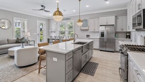 Una cocina moderna con una isla central, electrodomésticos de acero inoxidable e iluminación colgante.