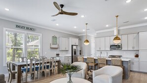 Una cocina moderna con armarios blancos, un comedor con mesa y sillas de madera y un ventilador de techo.
