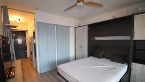 A modern bedroom with a bed, wardrobe, and ceiling fan. - Fully equipped cabin studio 4 people parking (LE GRAU DU ROI)