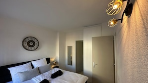 A modern bedroom with a large bed, a wall clock, and a unique light fixture.