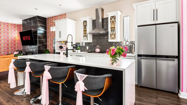 A modern kitchen with a central island, bar stools, a stainless steel refrigerator, and a TV displaying 'NETFLIX'. - Lipstick n Legends 2 Miles Downtown, Hot Tub, Pool (Nashville)