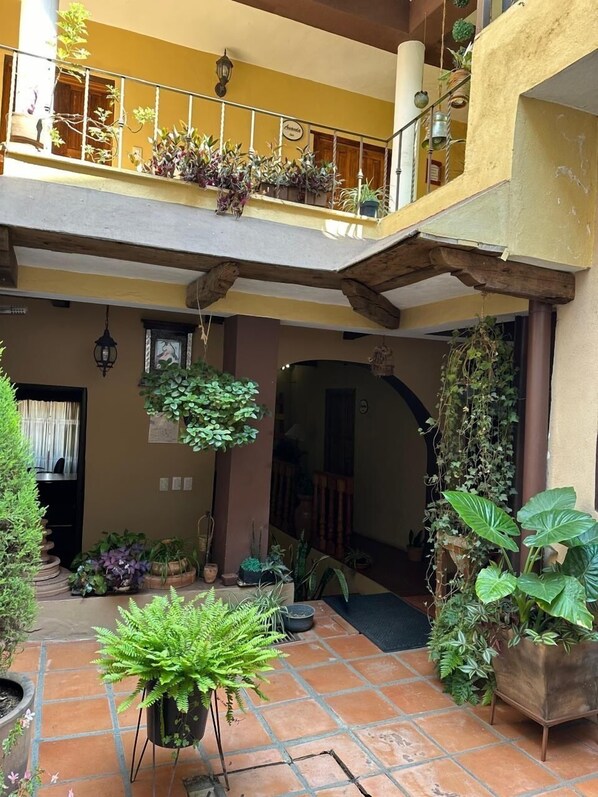 Un patio con baldosas de terracota, plantas en macetas y barandilla de madera para balcón.