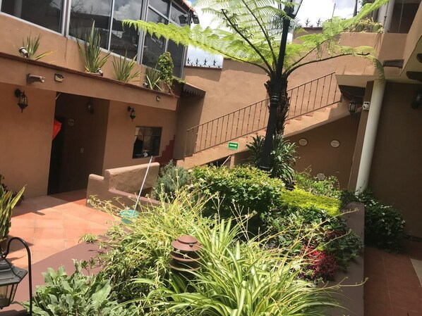 Un patio con escaleras, plantas en macetas y un pequeño espacio para sentarse.