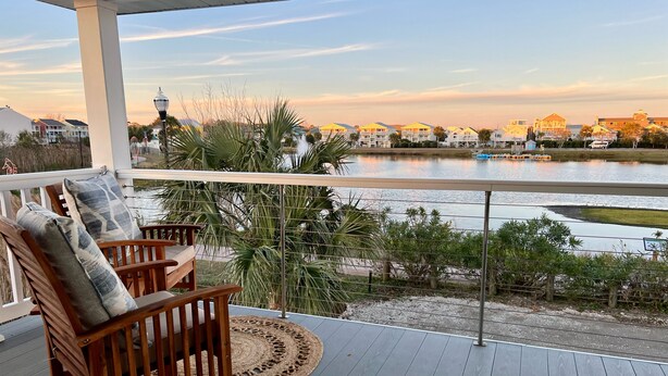A wooden deck with a view of a lake and buildings in the background. - Incredible Water Views on Carolina Beach - The Happy House (Carolina Beach)
