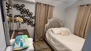 Ein Schlafzimmer mit Bett, Schminktisch, Spiegel und einer Wandleuchte.