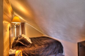 Een slaapkamer met een bed, een nachtkastje met een lamp en een gordijn.