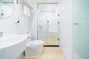 Une salle de bain moderne avec une douche à parois de verre, un lavabo blanc et des toilettes.