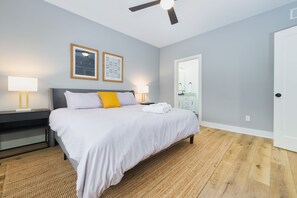 A bedroom with a bed, two bedside lamps, a ceiling fan, and a framed picture on the wall.
