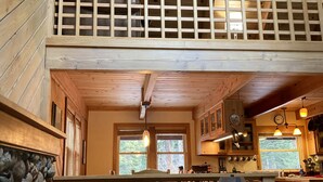 Ein Holzblockhaus-Innenraum mit Essbereich, Küche und einem Balkon mit Hollerkerung.