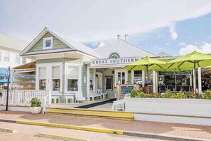 A building with a sign reading "GREAT SOUTHERN" and outdoor seating with green umbrellas. - A+ Location across from beach. Free bikes & beach equipment! (Santa Rosa Beach)