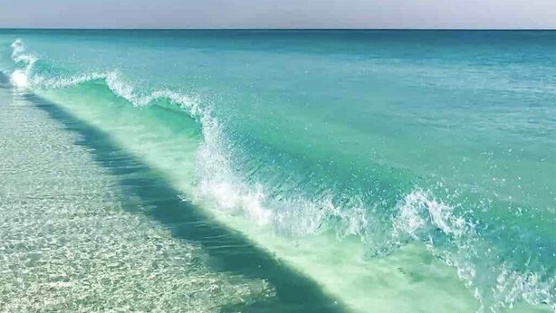 Una platja amb aigua turquesa cristal·lina i onades suaus.