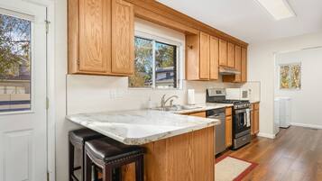 A kitchen with wooden cabinets, a marble countertop, a built-in oven, and a large window.