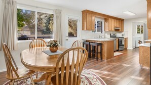 Una cocina moderna con armarios de madera, una isla central y un comedor con mesa y sillas de madera.