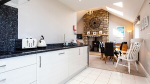 A modern kitchen with white cabinets, a granite countertop, and a built-in stove. - Harbour Lights House (Seahouses)