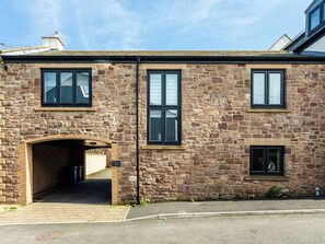 A stone building with two windows, a brick archway, and a small door. - Harbour Lights House (Seahouses)