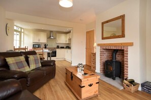 A cozy living room with a brown leather sofa, a wooden chest, and a fireplace. - Castle View (Bamburgh)