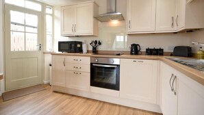 A modern kitchen with white cabinets, a stainless steel oven, a microwave, and a coffee maker.