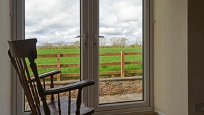 A room with a large sliding glass door leading to a grassy field with a wooden fence. - Dunrovin (Chathill)