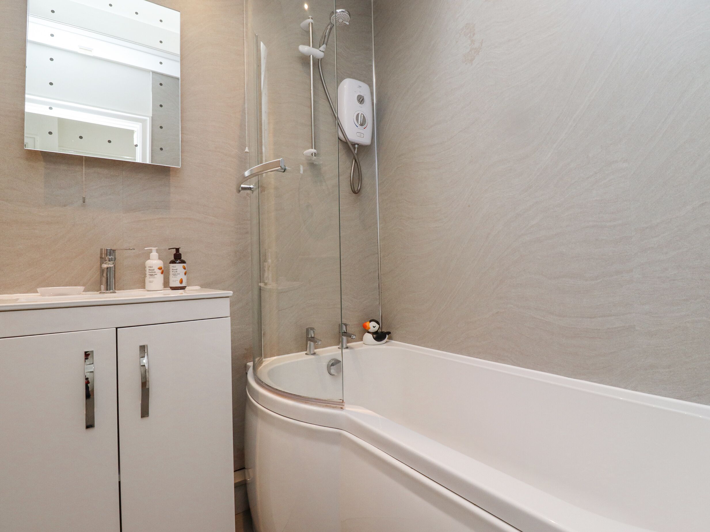 A modern bathroom with a freestanding bathtub, a glass shower enclosure, and a vanity with a mirror and toiletries.