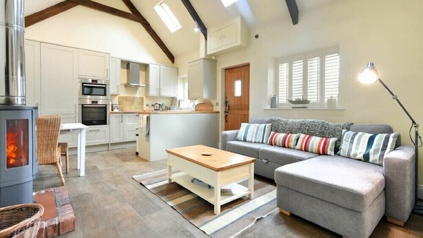 A cozy living room with a fireplace, a sofa, and a dining area. - Martins Cottage (Alnwick)