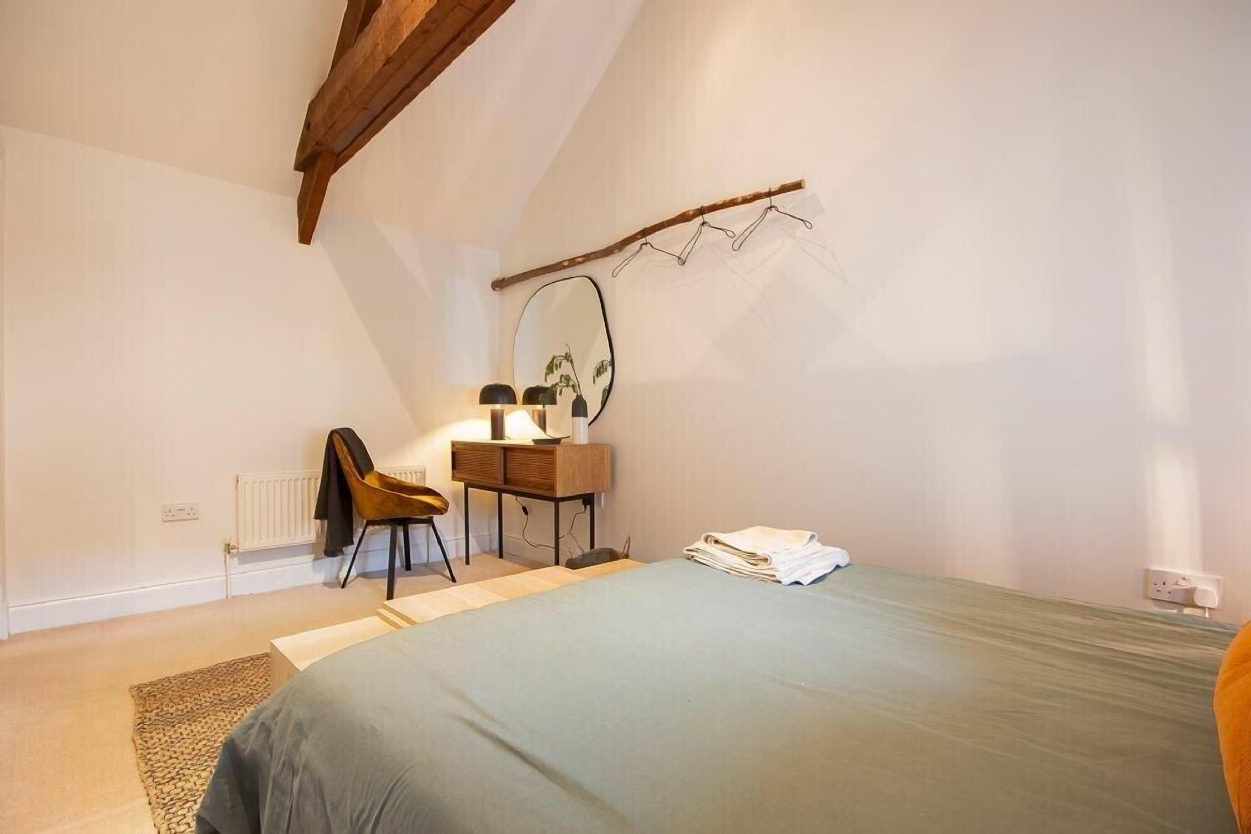 Une chambre à coucher avec un lit, un bureau avec une chaise, un radiateur et un miroir au mur.