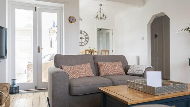 A living room with a grey sofa, a wooden coffee table, and a door leading outside.