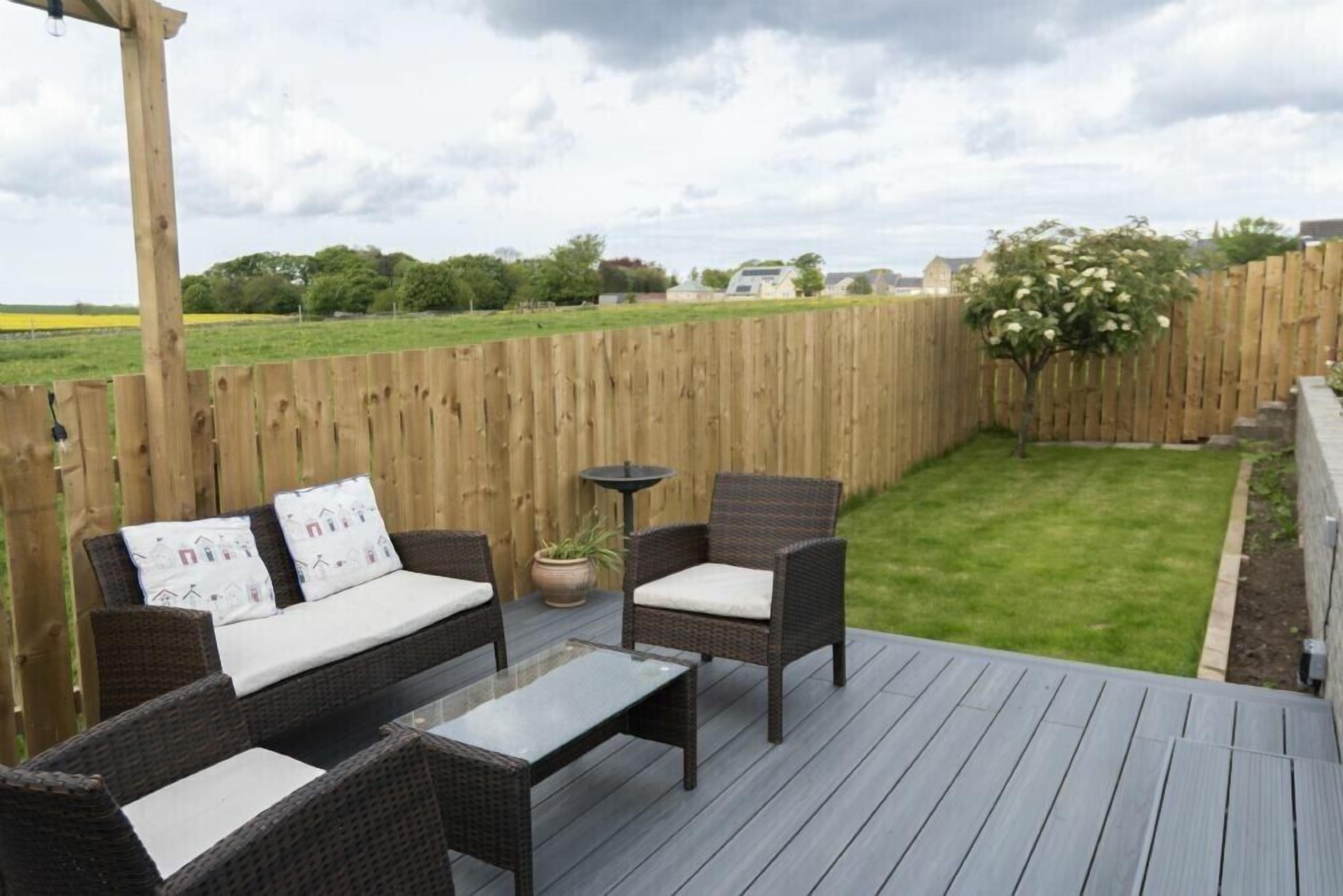 An outdoor deck with wicker furniture, a small table, and a potted plant.