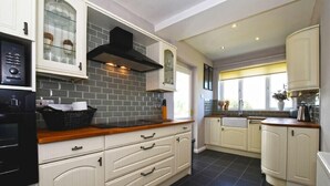 A kitchen with white cabinetry, a black tiled backsplash, and a wooden countertop.