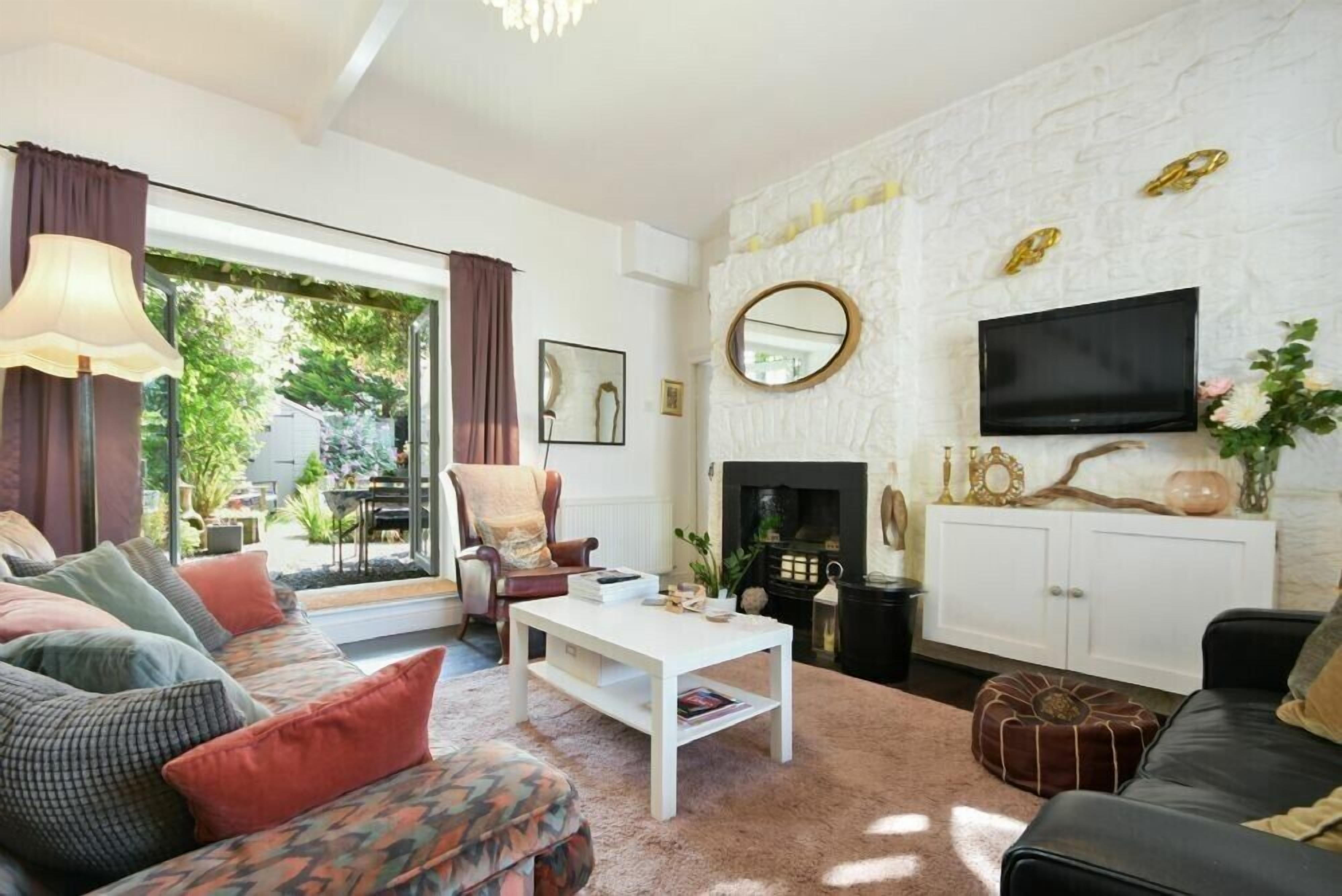 A living room with a sofa, armchair, coffee table, fireplace, TV, and a stone wall.