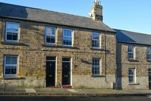 A stone building with multiple windows and doors, featuring a traditional architectural style.
