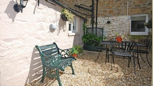 A stone building with a bench and outdoor seating area. - Crier Cottage (Alnwick)