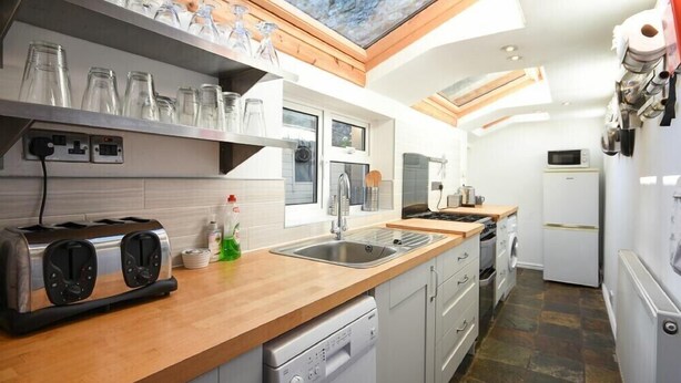 A modern kitchen with a skylight, stainless steel appliances, and a wooden countertop. - Crier Cottage (Alnwick)
