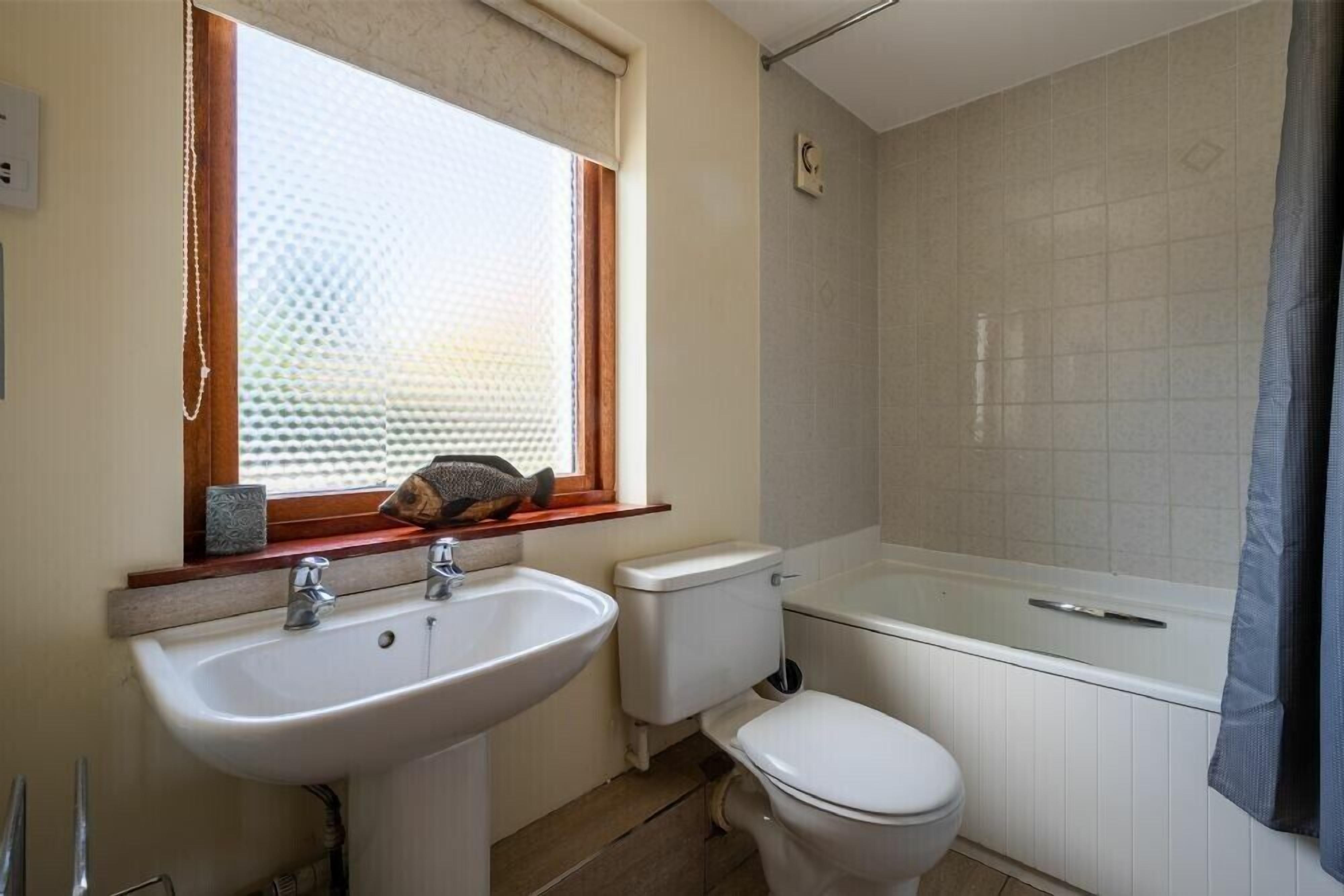 Et badeværelse med håndvask, toilet og badekar.