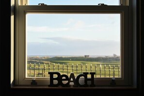 A window with the word "Beach" in front of a view of a golf course. - Mariners House (Alnwick)