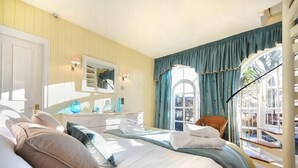 Una habitación de hotel con una cama grande, un tocador con espejo, una ventana con cortinas y vistas al exterior.