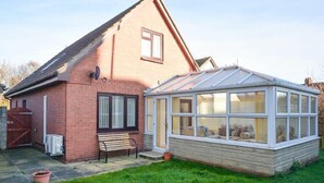 A brick house with a conservatory. - Annstead House (Seahouses)