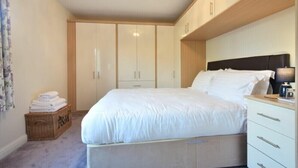 A bedroom with a bed, a nightstand, a dresser, and a wardrobe. - Annstead House (Seahouses)