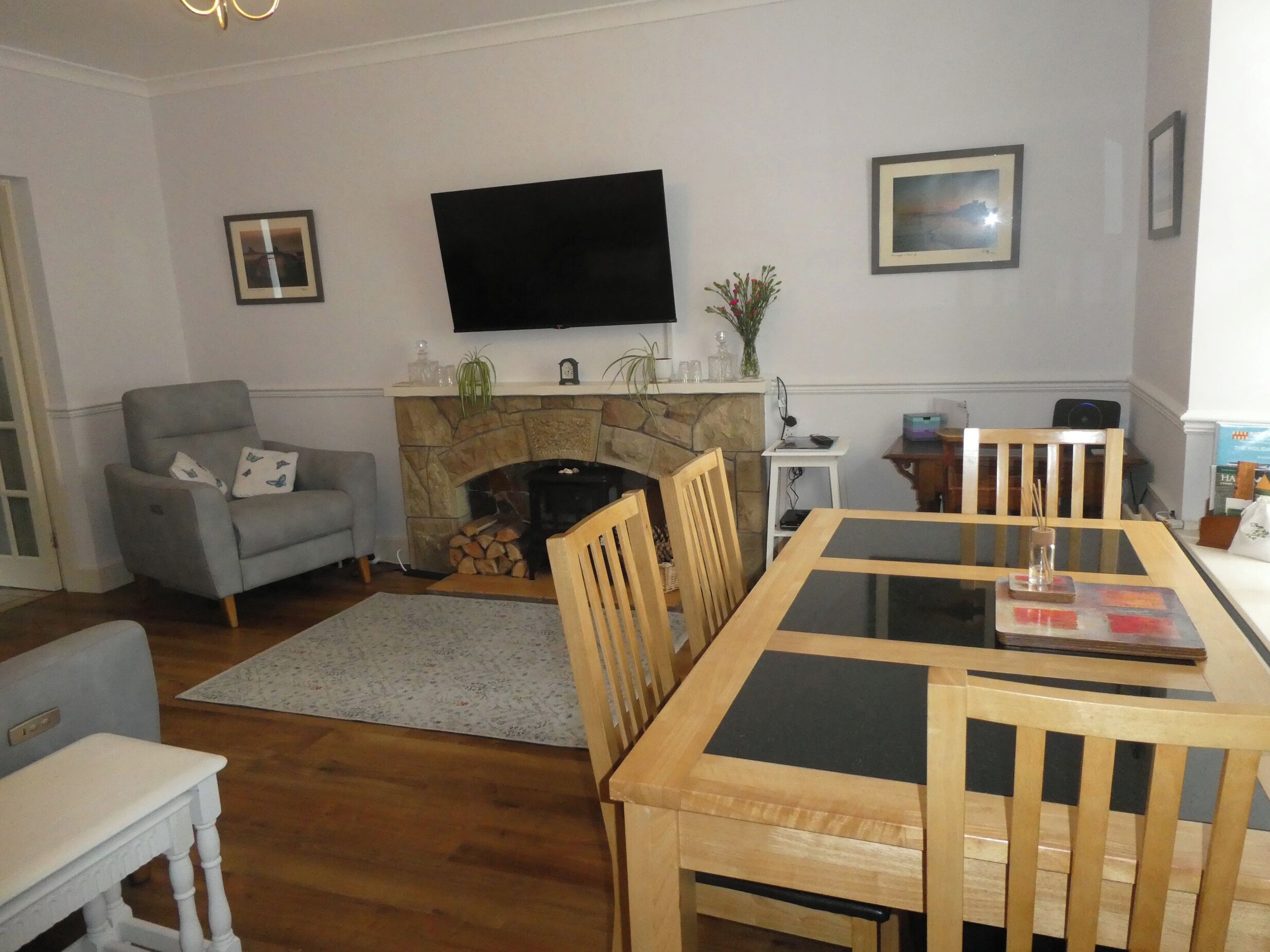A living room with a fireplace, a flat-screen TV, a dining table with chairs, and a small side table.