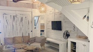 A spacious living area with a high ceiling, a ceiling fan, a round dining table, a sofa set, and a TV mounted on the wall. - Ma Case aux Antilles on Grand Case Beach! (Grand-Case)