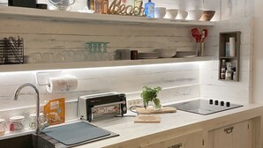 A kitchen with a white wooden countertop, a sink, a toaster, and a variety of bottles and jars on the shelf above. - Ma Case aux Antilles on Grand Case Beach! (Grand-Case)