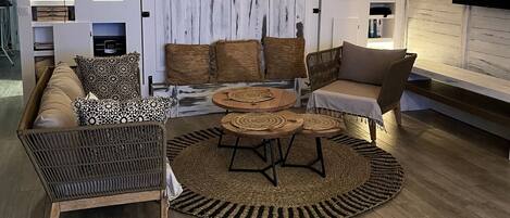 Ein modernes Wohnzimmer mit einer Couch, Sesseln, einem Couchtisch und einem Fernseher.