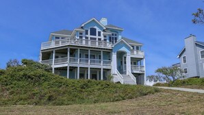 A large, multi-story house with multiple balconies and a prominent front porch.
