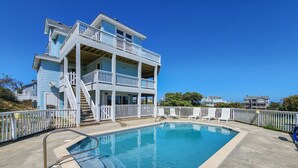 A two-story building with a pool, white railings, and a clear blue sky.
