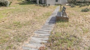 A two-story house with a front porch and a stone facade. - By Jove - Semi-Oceanfront 5 BR Beach Cottage w/Private Pool & Dogs Allowed (Southern Shores)