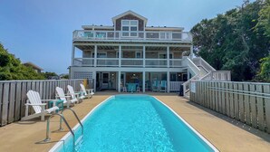 A pool area with a two-story building, outdoor seating, and a staircase leading to the upper level.